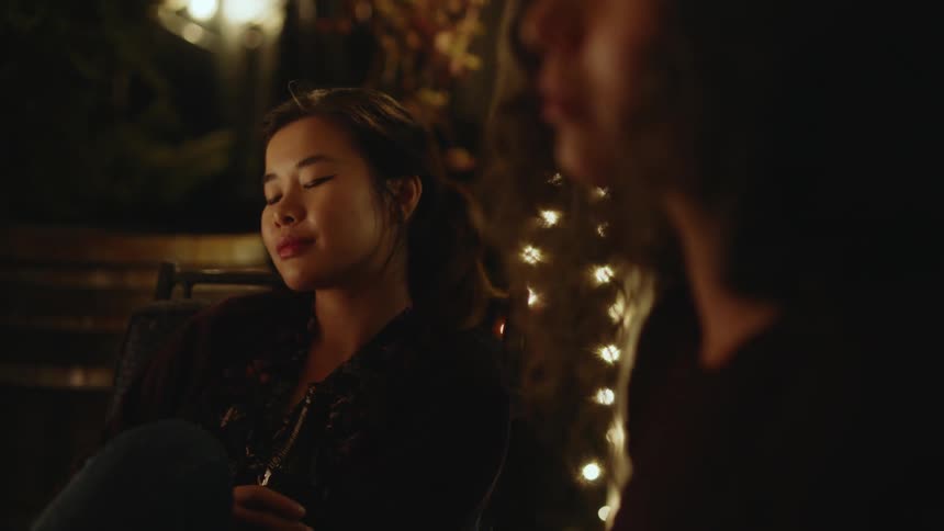 A woman sitting looking contemplatively and looking at the person sitting next to her