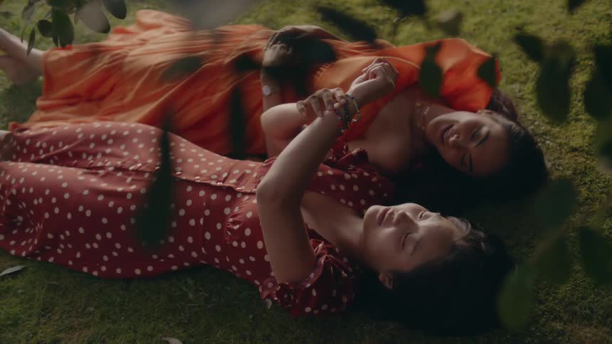 Two women are laying on a grass field together