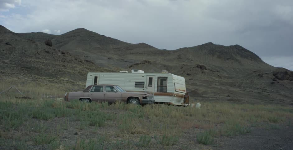 A vehicle and a recreational vehicle sit parked below a canyon
