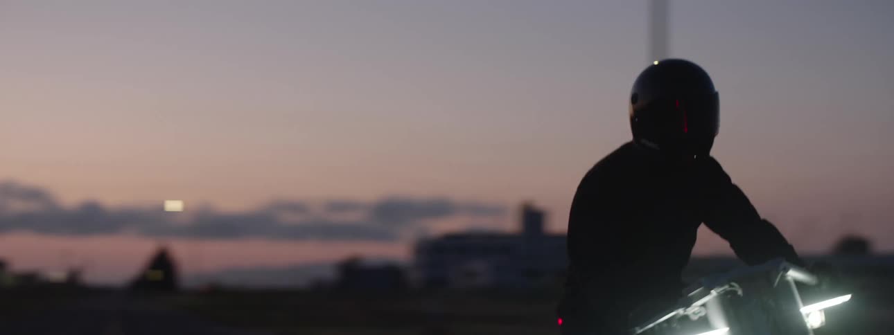 A person riding a motorcycle on a road during sunset