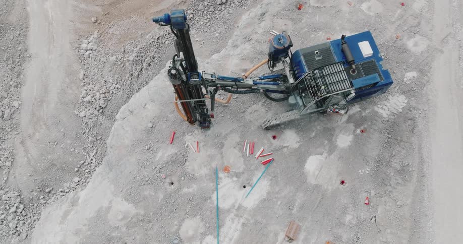 A large drilling machine is preparing holes for explosive charges