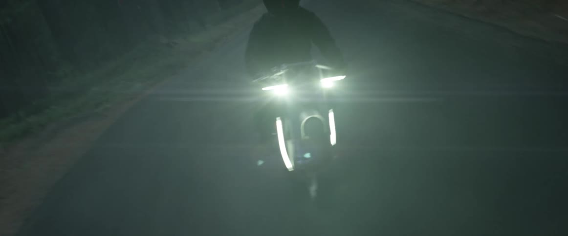 A man is riding a motorcycle through a rural area