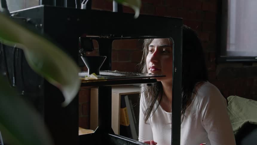 Close up of a woman supervising the process of a 3d printer