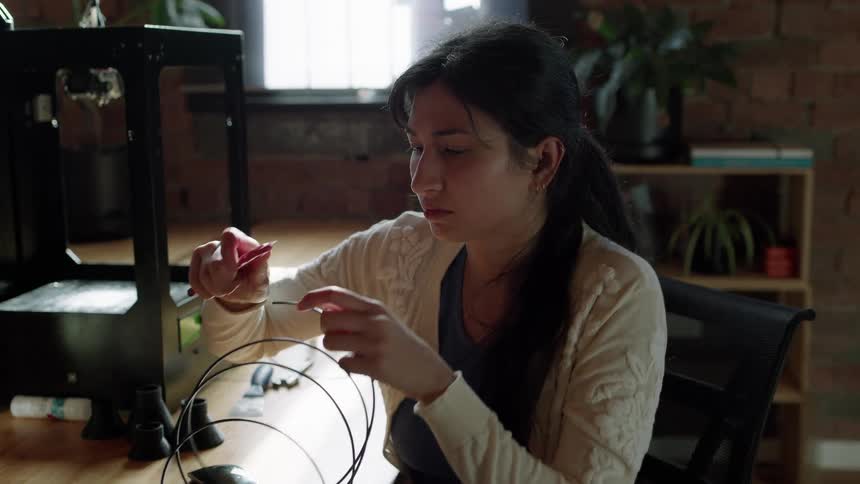 Young woman shaves the tip of a plastic filament with a blade