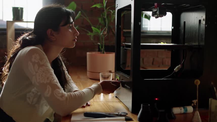 A woman sitting at a desk adjusting a dial to a machine in front of her