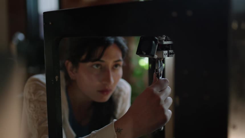 A young woman uses a wrench to adjust part of a machine