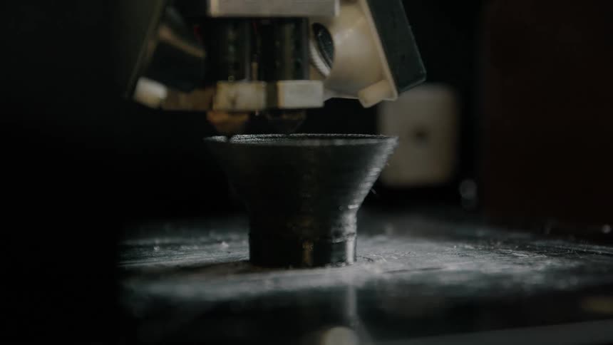 A three dimensional printer moves around and object it is creating