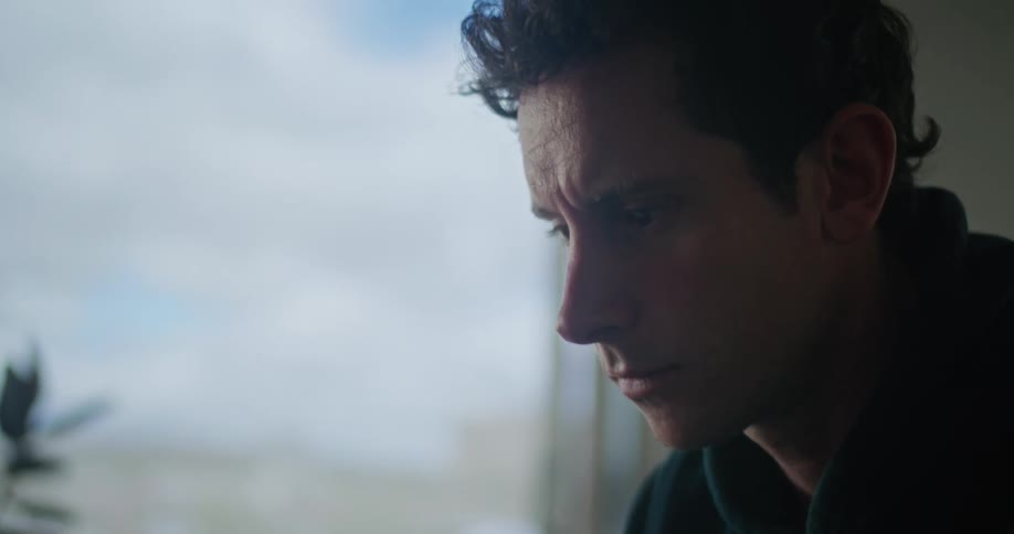 Close up of a young man sitting at a desk in his home office typing on a laptop