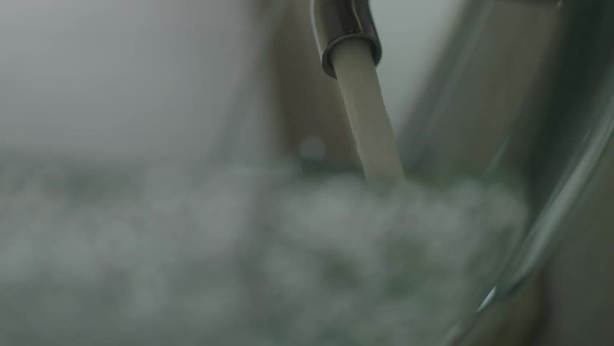 Water pouring out of a faucet into a container