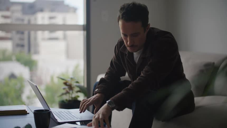 A man flips through his book and looks at a laptop