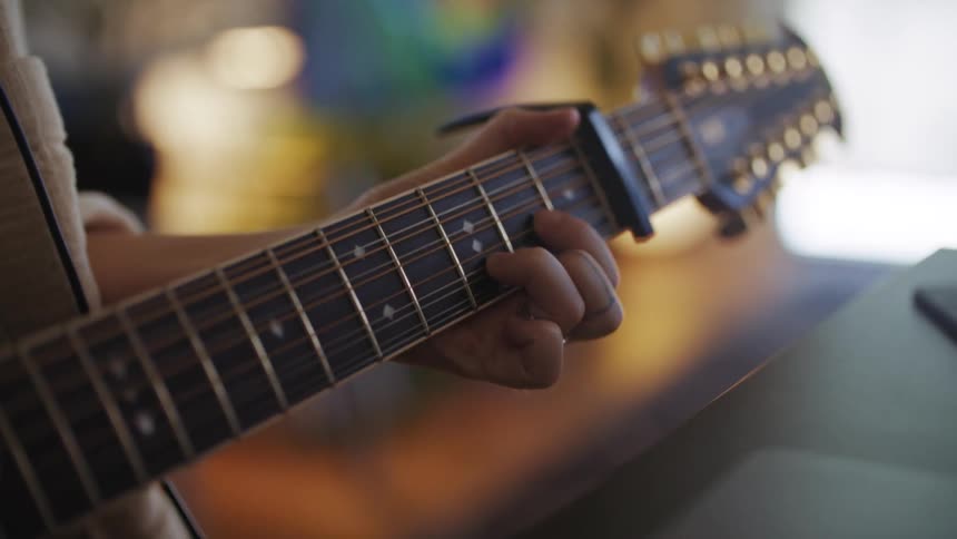 A person is practicing by playing a chord on a guitar