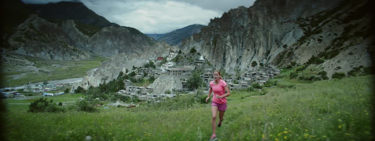 Active Woman Jogging Up Slope with Picturesque Mountain Town
