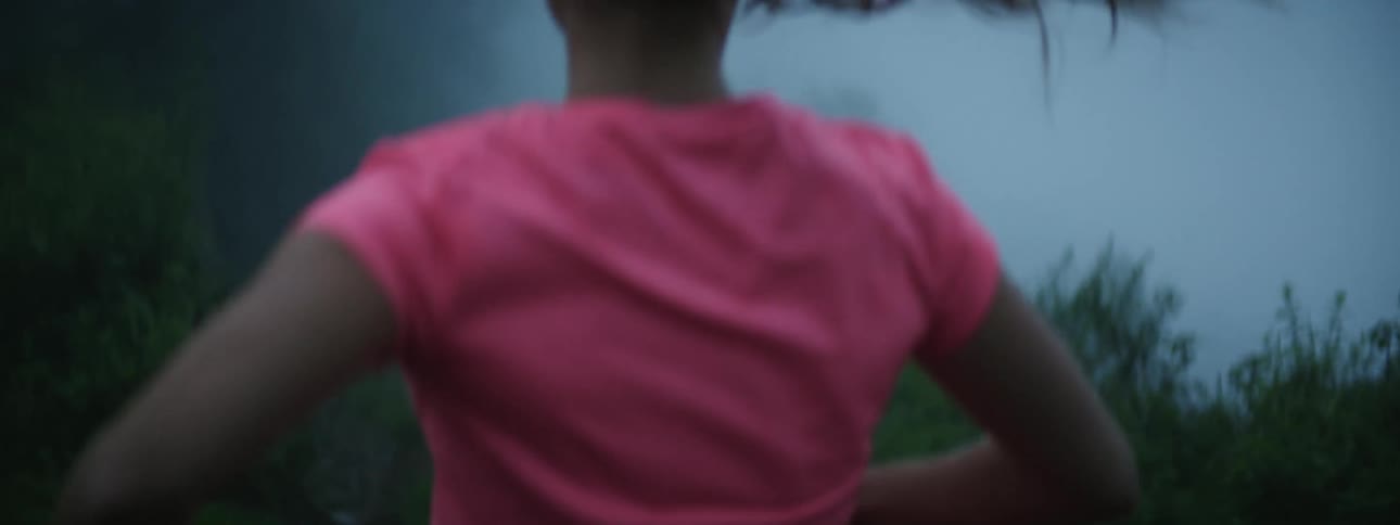 Young woman wearing a pink shirts jogging in the countryside covered in mist