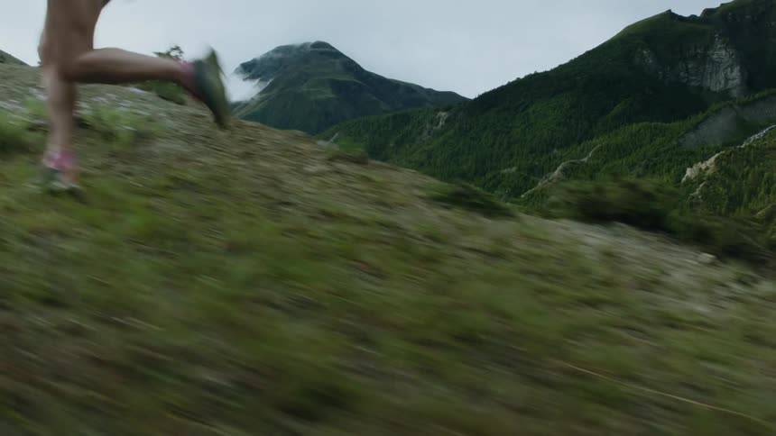 Close up of the legs of a woman running uphill on the slope of a mountain at daytime