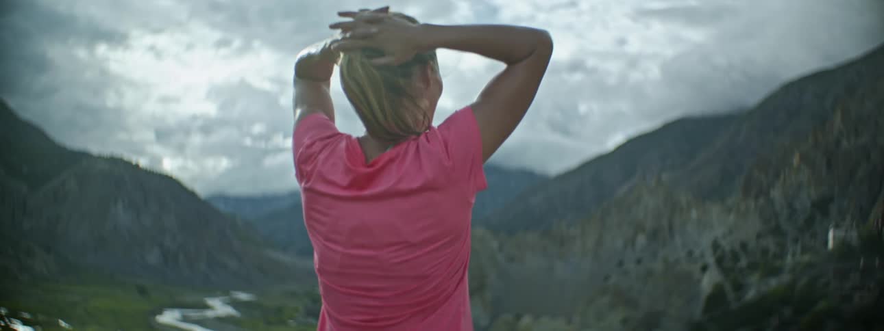 Back of a young woman looking at the valley from the top of a mountain at daytime