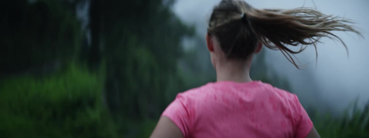 Blonde woman jogs along trail on foggy day