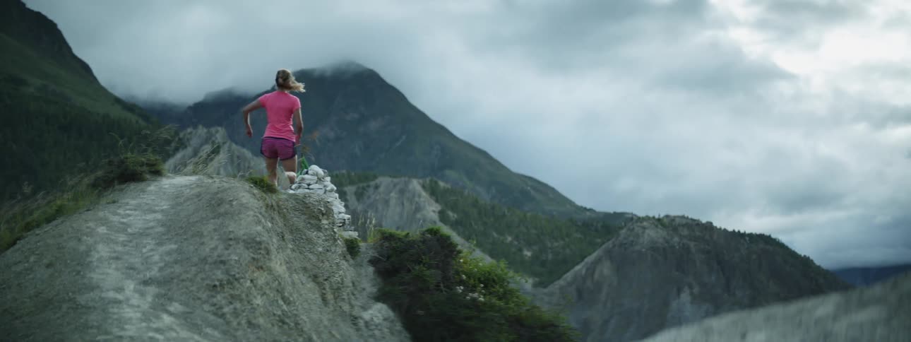 A woman is jogging outdoors up a mountain pass