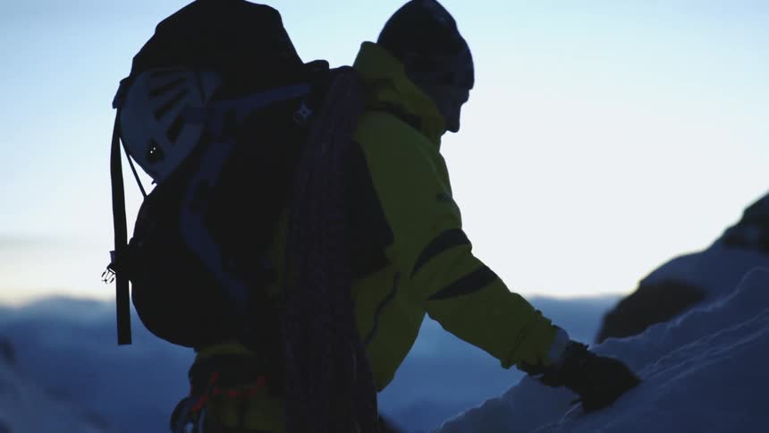A man is climbing up the mountain through the snow