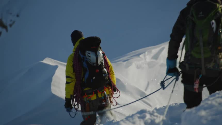 Two people tread through the snow on the mountain