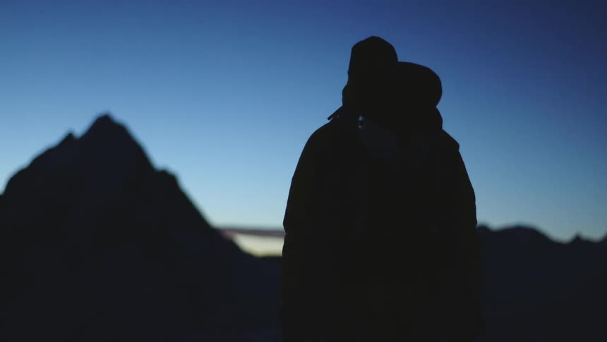 Man hiking with backpack through hills toward mountain at sunrise