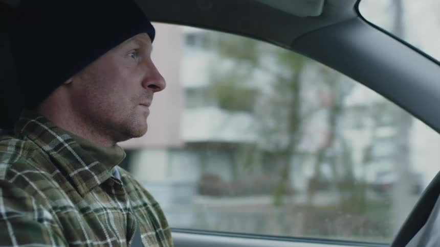 Interior view man wearing flannel and a beanie driving through the city