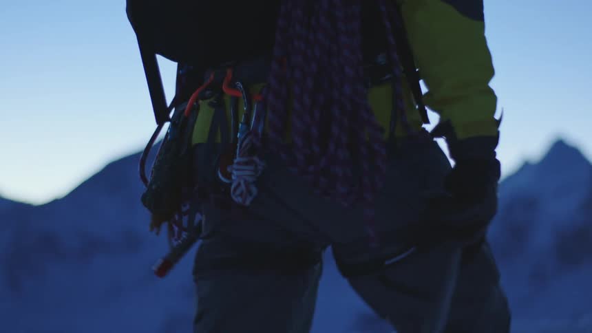 A man is walking on a hill with wires on his back carrying advanced technology equipment