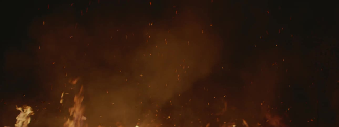 A burning wood with bright orange flames illuminating the night