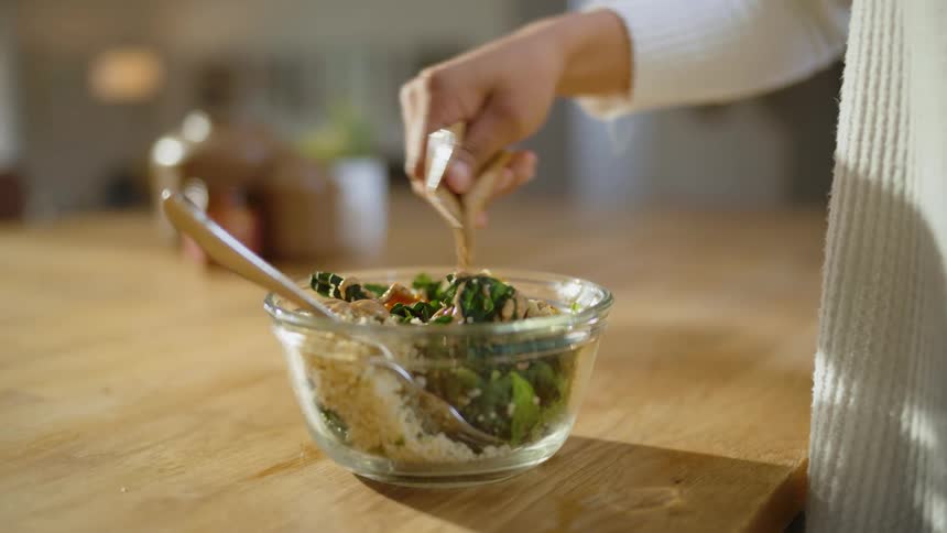 A woman is applying dressing to her salad