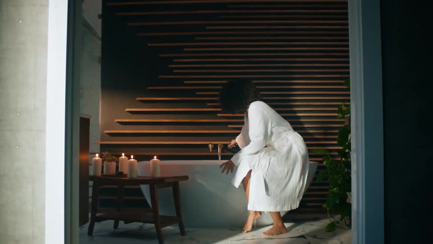 Woman walks into bathroom to run a bath