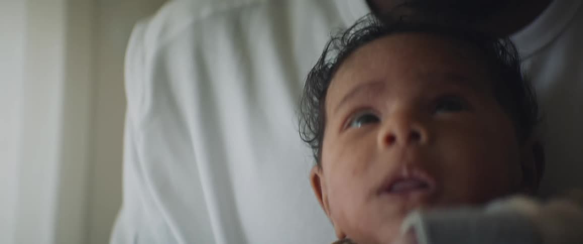 A close up of a babies face as he is being bounced in his fathers arms