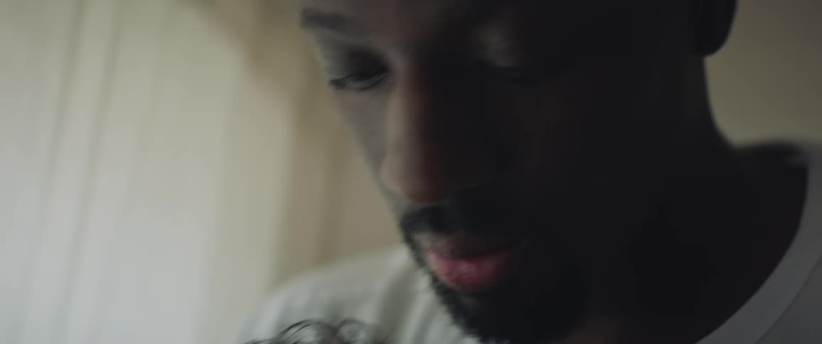 Father with white shirt rocks baby in his arms in room