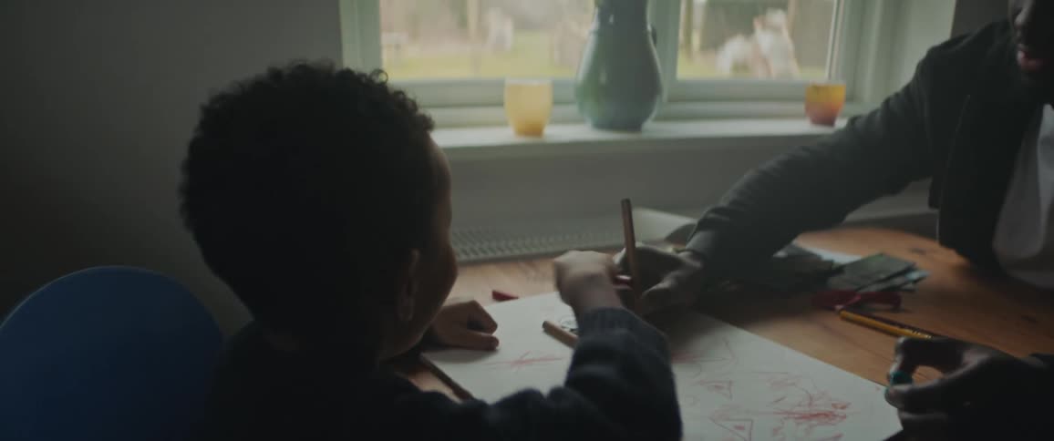 A man and child sitting at a table drawing and laughing