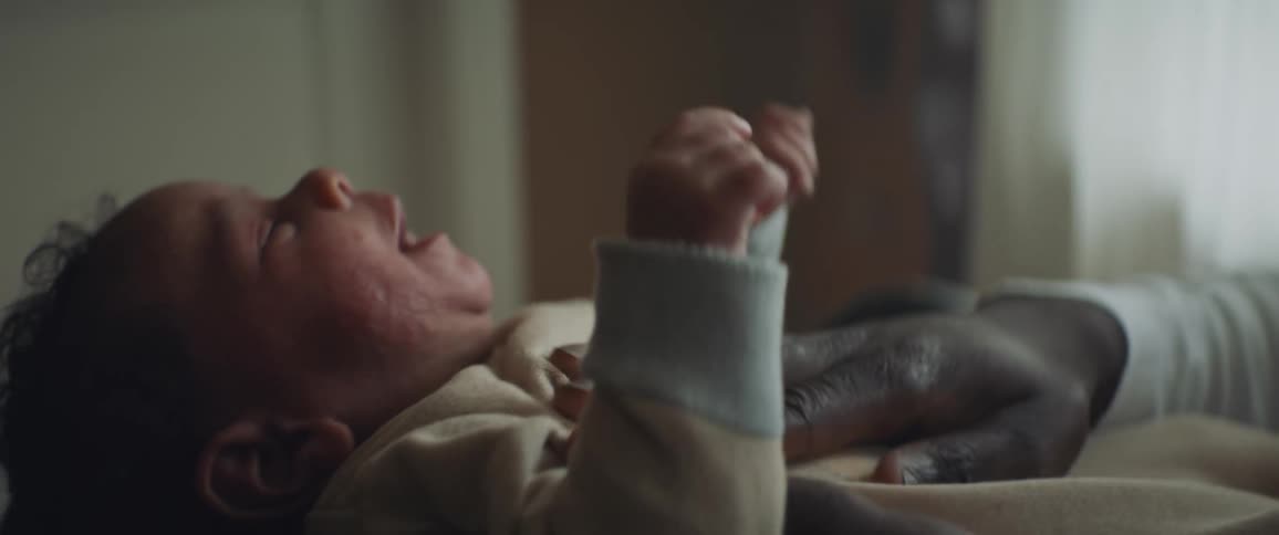 Adult rocking a crying infant while rubbing their chest and belly