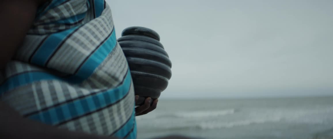 A woman is carrying an urn on the beach