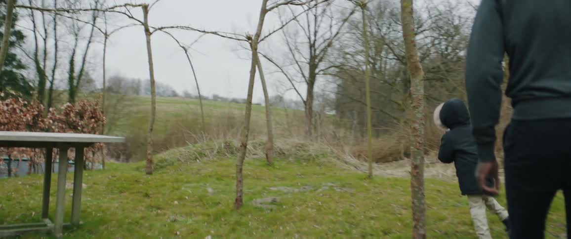 Father follows his son running in the backyard playing with a hobby horse