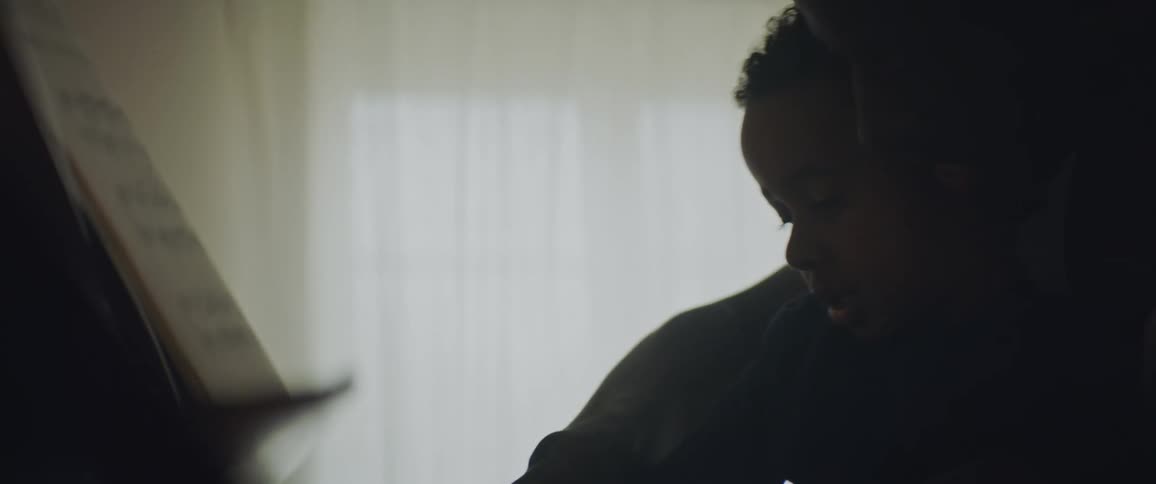 Silhouette of a father teaching his son how to play piano at home