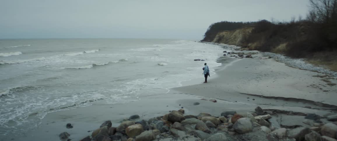 Man stands on the shoreline of a beach looking at the sea at daytime