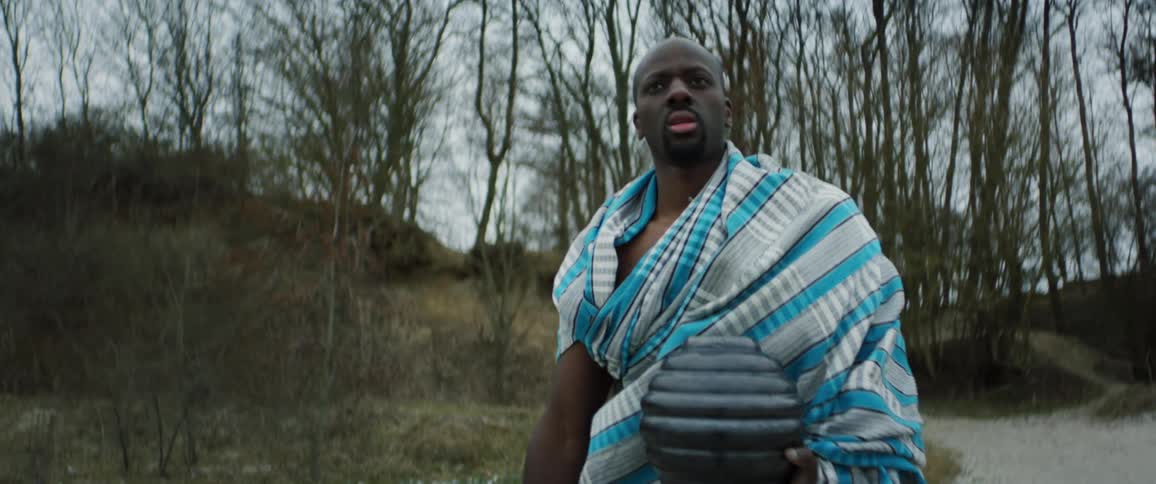A man is holding an object and walking through the wilderness