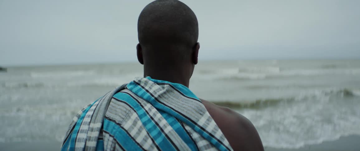 Man with towel walks towards ocean on a cloudy day on the beach