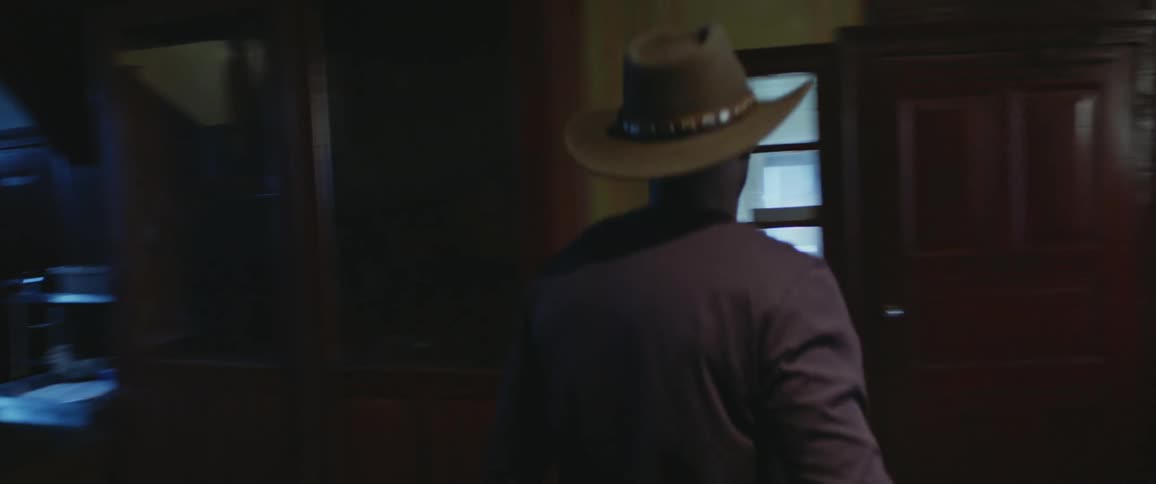 A man is walking downstairs and exits a room of a building