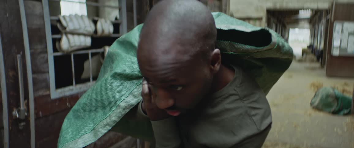 Man hauls large sack along alley past buildings