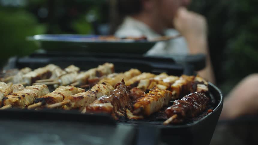 Two people are grilling food outdoors during the spring