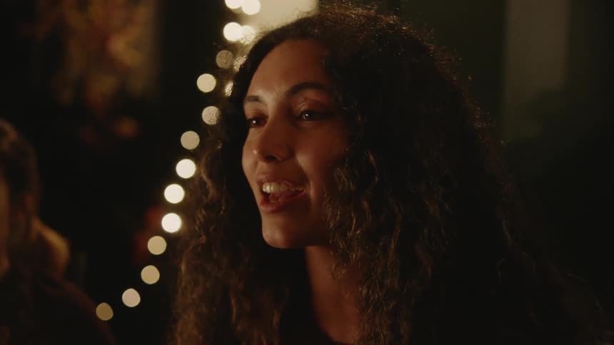 A woman is smiling and talking to friends in a restaurant