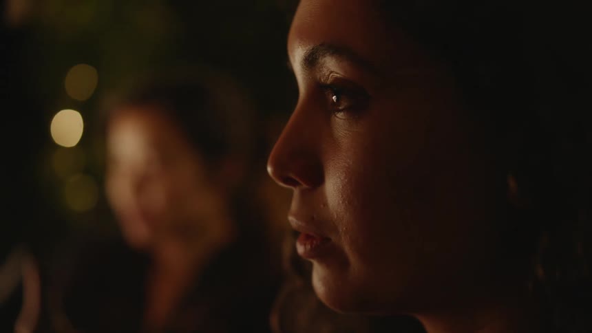 A close up of a womans face as she talks to someone in front of her