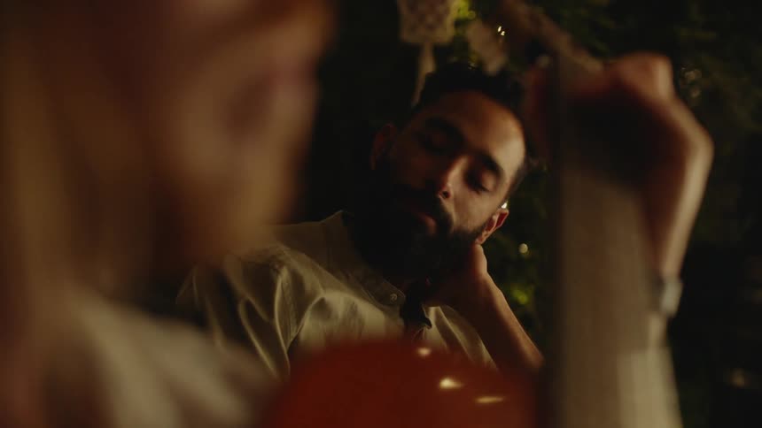 A man listens to another man play music