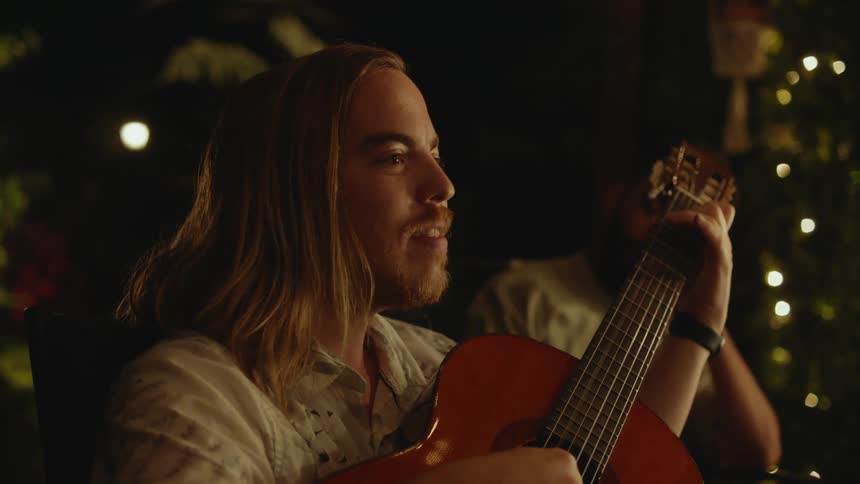 A man is playing an acoustic guitar as he sings