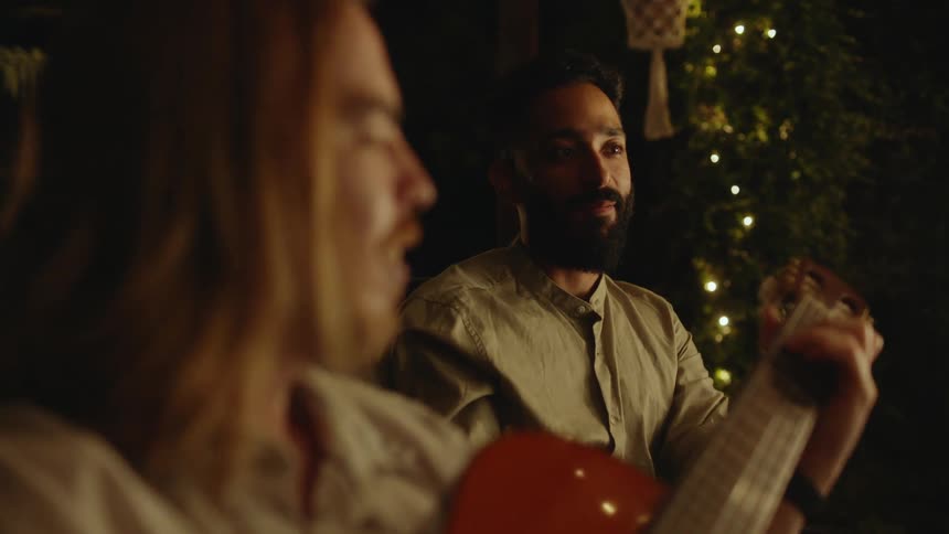 Two friends are playing guitar while sitting outdoors