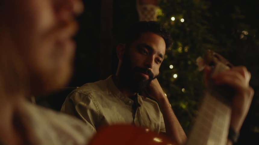 A man is listening to someone play guitar