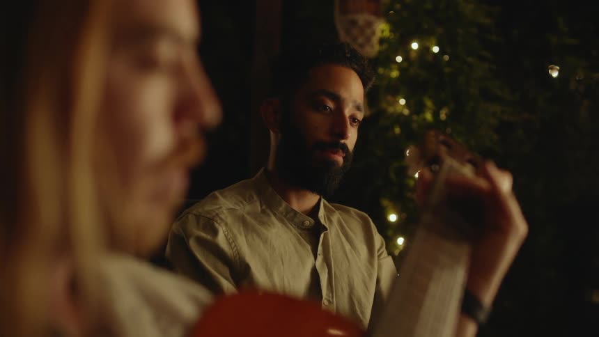 Two men sitting outside and playing guitar but they both have sad expressions on their faces