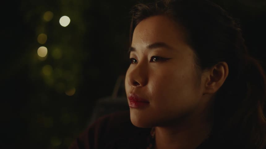 A woman is smiling and sitting outdoors at night